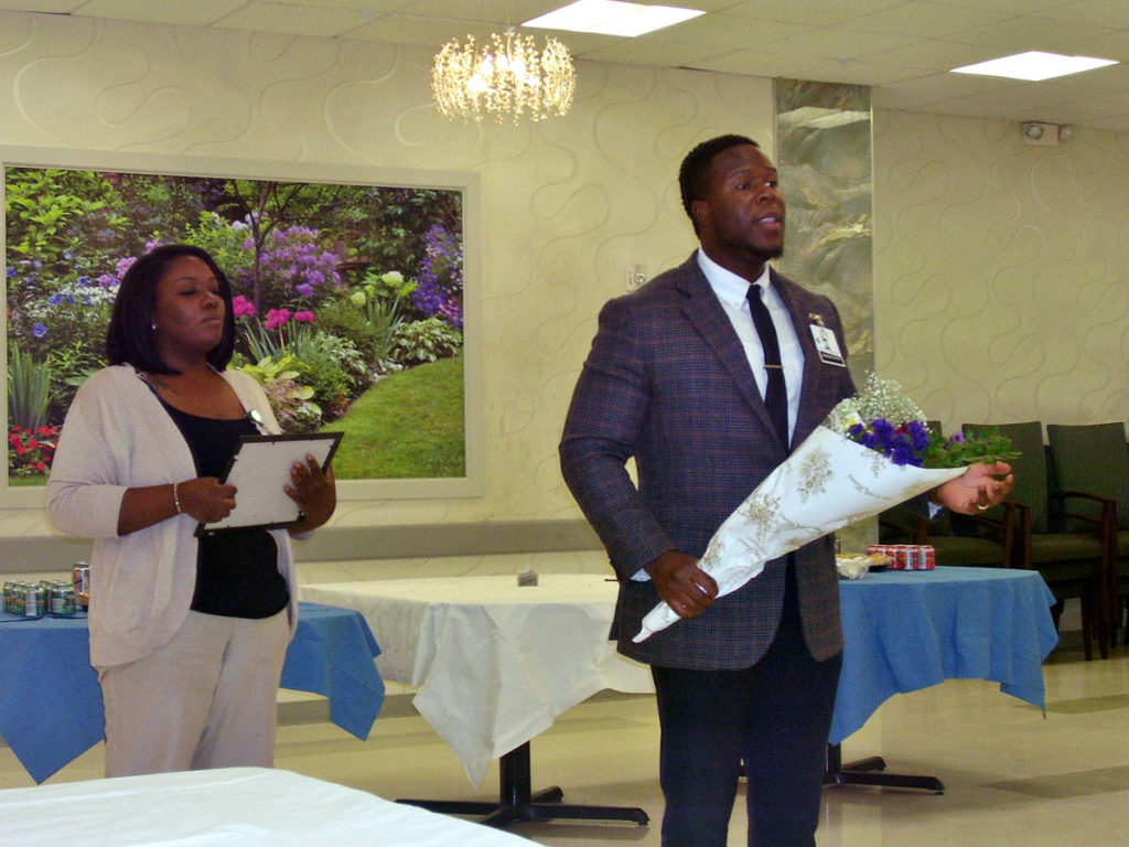 Ellis Gray being awarded employee of the month and flowers by man in suit.