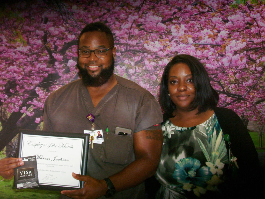 Marcus Jackson posing with Employee of the Month award with female.